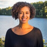 Sarah Childress headshot, Sarah is standing in front of a body of water wearing a black top.